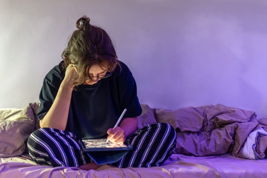 Osoba koristi mobitel u krevetu navečer, plavo svjetlo ekrana može smanjiti proizvodnju melatonina